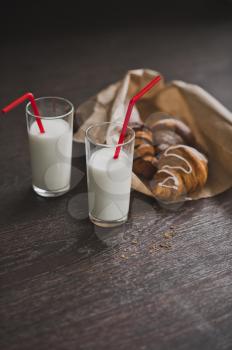 Bag with croissants and glasses of milk for Breakfast.