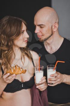 A man and a pregnant woman drink milk from glasses.