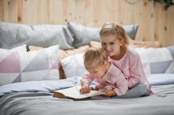 Older sister reads bedtime stories for younger sister.