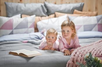 Older sister reads bedtime stories for younger sister.