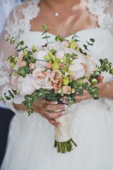 Unusual composition of the bouquet in the hands of a woman in a white dress.