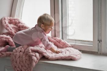 Happy child playing on a bright windowsill.