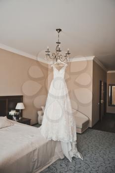 A gorgeous wedding dress hangs in the middle of the room.