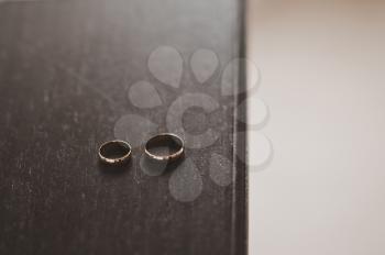 Two wedding rings on a dark wood table.