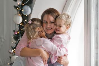 Mom enjoys playing with little daughters at the window.