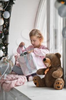 A little girl in a pink dress with a huge Christmas gift.