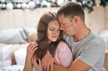 Newlyweds gently hugging on the background of the Christmas tree.