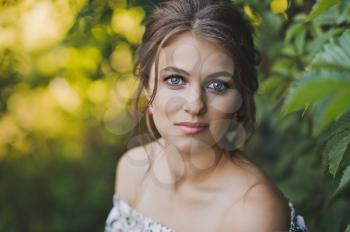 Large portrait of a girl sitting among the ivy leaves.