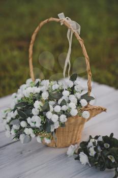 Wicker basket with a handle and a bouquet of white violets.