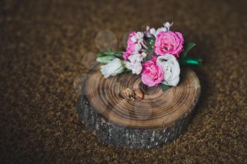Gold rings and a boutonniere on a tree cut.