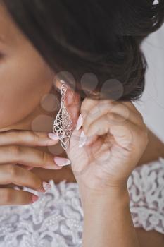 The girl shows the earring on her ear.