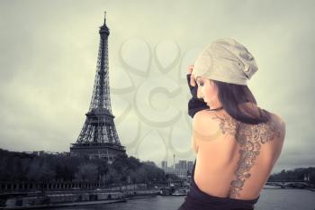 girl with a tattoo stands on the banks of the Seine near the Eiffel Tower. dramatic portrait