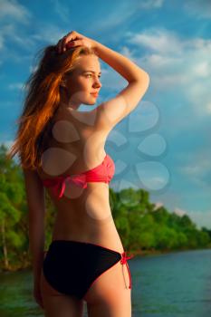 beautiful young blond woman in a swimsuit on the beach resting enjoying the evening sun and good weather