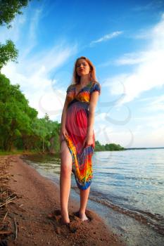 Girl in dress walking on the sea coast in the trees along the sandy beach. summer evening