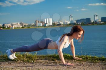 athlete is pushed outside by the river against the background of the city on a summer evening