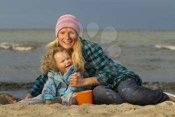 Mother and daughter sitting at the sea . early autumn , end of summer . Family vacation by the sea