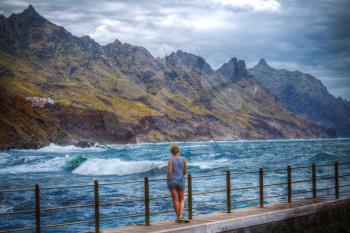 girl ocean Tenerife. He looks at the rocks in Beniho