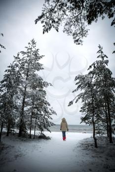 girl walking by the sea in winter. cold dark day in Northern Europe