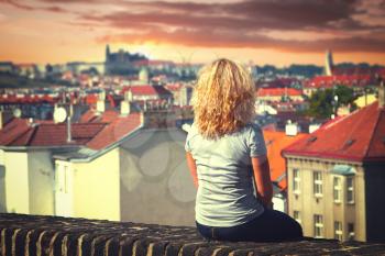 girl sitting on the roof of a house in Prague. top view of the city