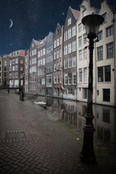 Traditional old buildings in Amsterdam, the Netherlands . night shining moon and stars.