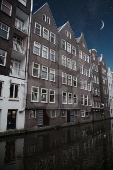 Traditional old buildings in Amsterdam, the Netherlands . night shining moon and stars.