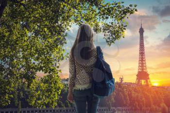 girl with a backpack looking at the Eiffel Tower