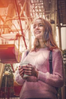 girl holding a glass of coffee in an amusement park