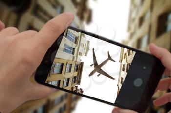 photograph a flying plane over the city on a smartphone