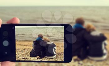 photographed on a smartphone sitting at the ocean couple