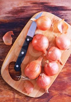 raw onion on wooden board and on a table
