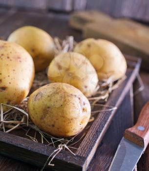 raw potato in wooden box and on a table