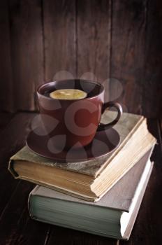 tea with lemon in cup and old books