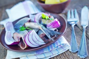 herring with onion in bowl and on a table