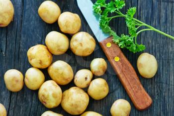 raw potato and knife on the wooden board