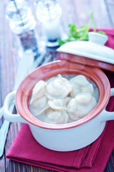 boiled pelmeni in bowl and on a table
