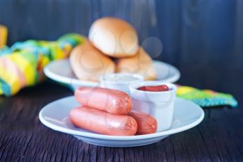 buns and sausages on white plate and on a table