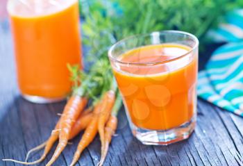 fresh carrot juice in the glass and on a table