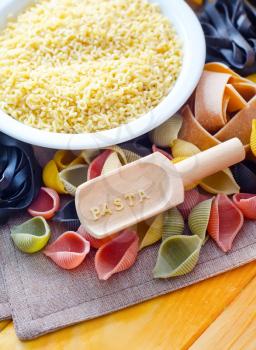 assortment of raw pasta and wheat on wooden background
