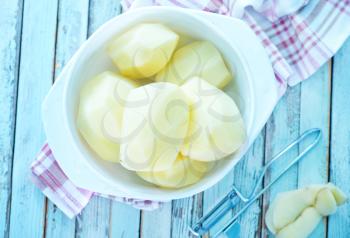 raw potato in bowl and on a table