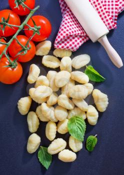 raw gnocchi and basil leaves on black table