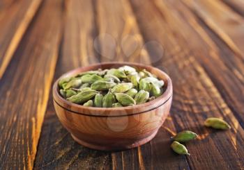 cardamon in wooden bowl and on a table