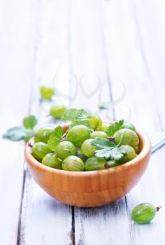 green gooseberry in bowl and on a table