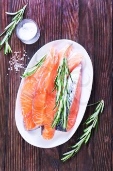 fresh salmon with rosemary on plate and on a table