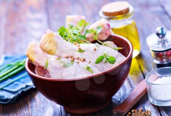 raw chicken legs in bowl and on a table