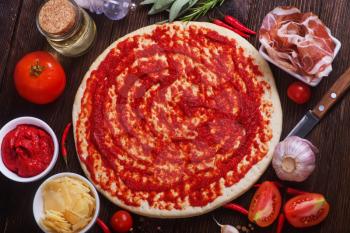 pizza and ingredients on the wooden table