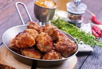 fried meat balls in pan and on a table