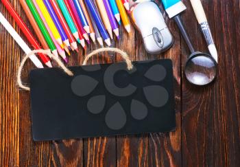school supplies on the wooden table, black board and school supplies