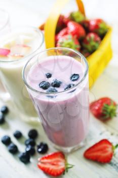 yogurt with fresh berries in glass and on a table