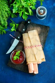 fresh sausages in paper and on a table