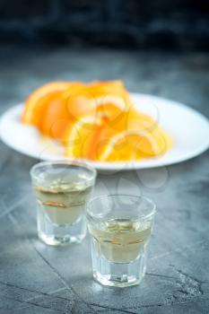 licuor in glass and fresh orange on a table